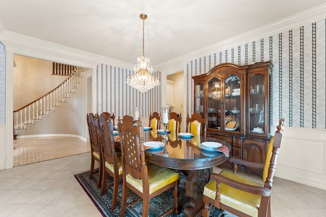 dining area featuring wallpapered walls, light tile patterned floors, ornamental molding, an inviting chandelier, and stairs