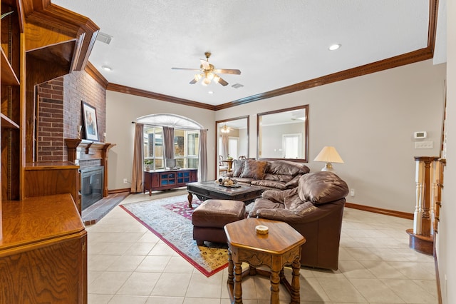 living room featuring light tile patterned floors, a ceiling fan, a glass covered fireplace, ornamental molding, and a textured ceiling