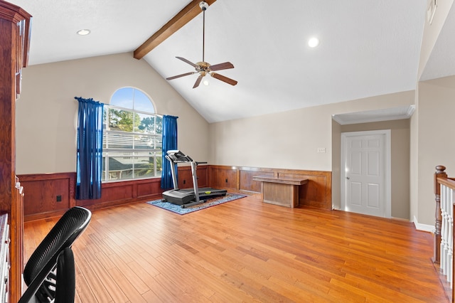 exercise room with lofted ceiling, light wood finished floors, a ceiling fan, and wainscoting