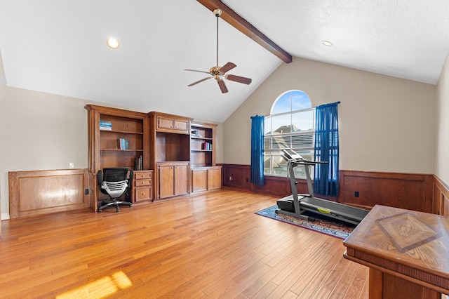 office featuring a wainscoted wall, ceiling fan, vaulted ceiling with beams, a textured ceiling, and light wood-style floors