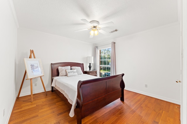 bedroom with baseboards, ornamental molding, visible vents, and light wood-style floors