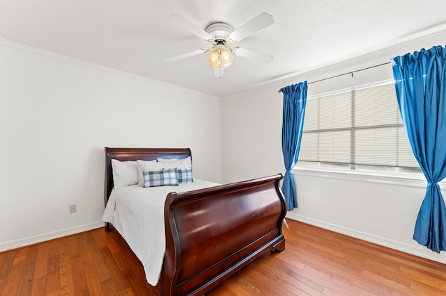 bedroom with crown molding, ceiling fan, baseboards, and wood finished floors