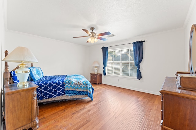 bedroom featuring baseboards, visible vents, a textured ceiling, crown molding, and light wood-type flooring