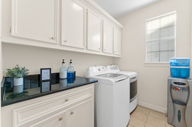 laundry area with washing machine and dryer, light tile patterned flooring, cabinet space, and baseboards