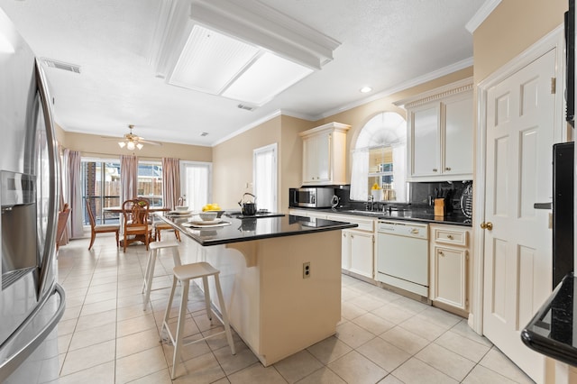 kitchen featuring light tile patterned floors, dark countertops, visible vents, appliances with stainless steel finishes, and a kitchen island