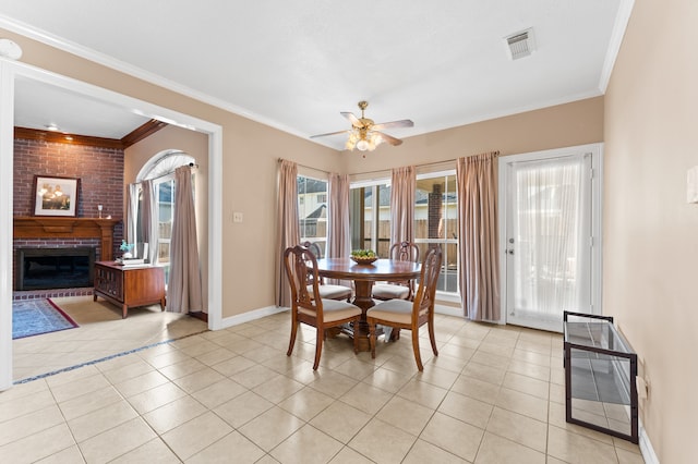 dining area with light tile patterned floors, a fireplace, visible vents, and crown molding