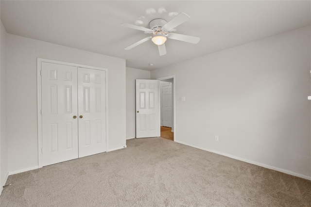 unfurnished bedroom with a closet, carpet, a ceiling fan, and baseboards