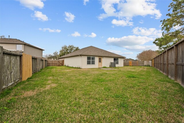 back of property featuring central air condition unit, stucco siding, a fenced backyard, and a yard