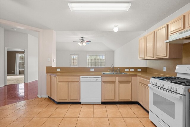 kitchen with a peninsula, white appliances, a sink, and light brown cabinetry