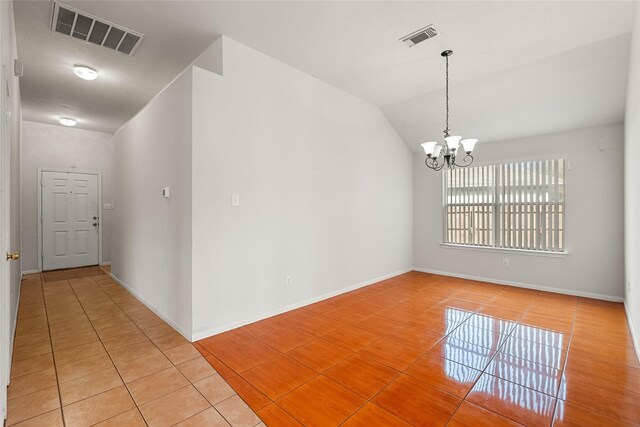 empty room with vaulted ceiling, light tile patterned flooring, visible vents, and an inviting chandelier