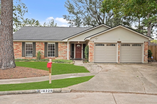 single story home featuring a front yard, brick siding, driveway, and an attached garage