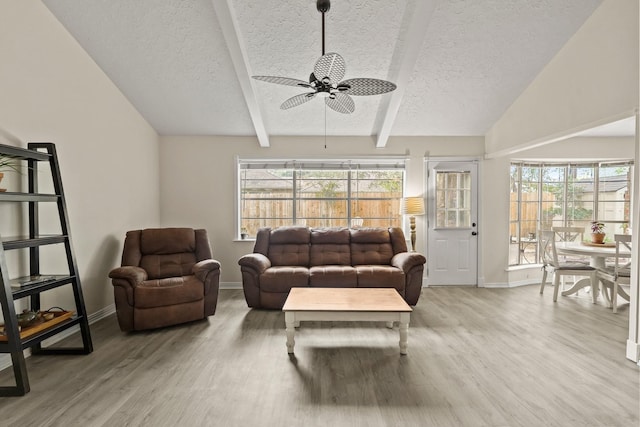 living room with lofted ceiling with beams, a textured ceiling, wood finished floors, and a healthy amount of sunlight