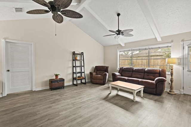 living room featuring a textured ceiling, lofted ceiling with beams, wood finished floors, and visible vents