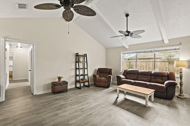 living room featuring attic access, visible vents, wood finished floors, vaulted ceiling with beams, and a textured ceiling