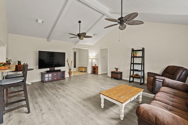 living area featuring wood finished floors, visible vents, a ceiling fan, baseboards, and beam ceiling