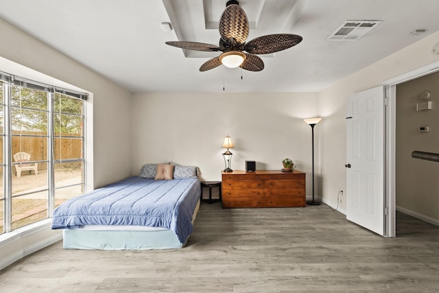 bedroom featuring baseboards, multiple windows, visible vents, and wood finished floors