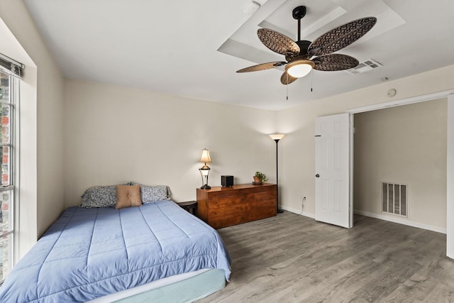 bedroom featuring baseboards, wood finished floors, visible vents, and a ceiling fan