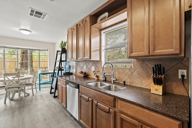 kitchen with visible vents, brown cabinetry, a sink, light wood-type flooring, and dishwasher