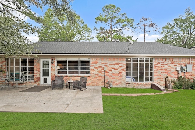 rear view of property with a patio area, a shingled roof, a lawn, and brick siding