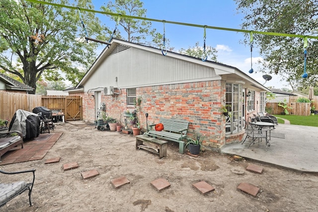 back of house with a patio area, a fenced backyard, a gate, and brick siding