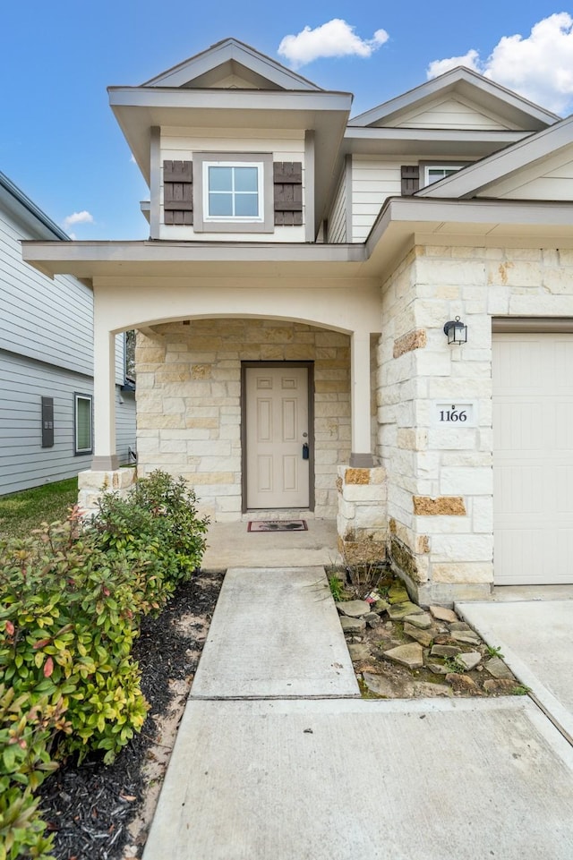 property entrance with an attached garage, stone siding, and a porch