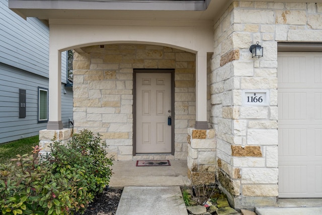 view of exterior entry with a garage and stone siding