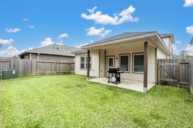 rear view of house featuring a yard, a patio, and a fenced backyard