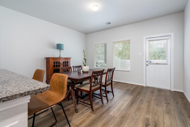 dining area with light wood-style floors, visible vents, and baseboards