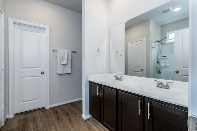 full bath featuring double vanity, baseboards, a sink, and wood finished floors