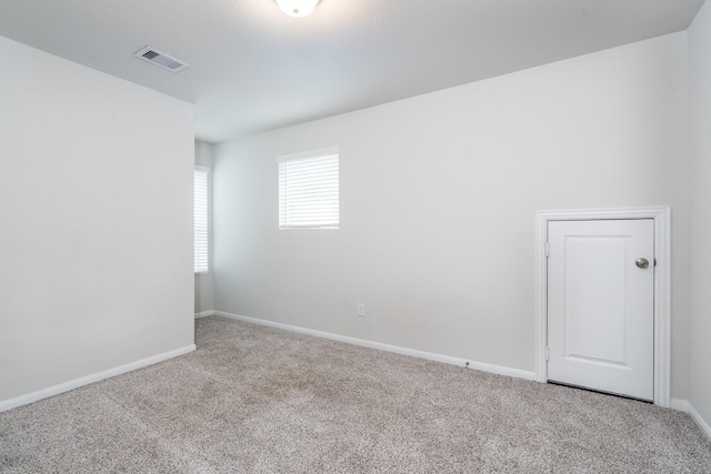 spare room with carpet floors, baseboards, and visible vents