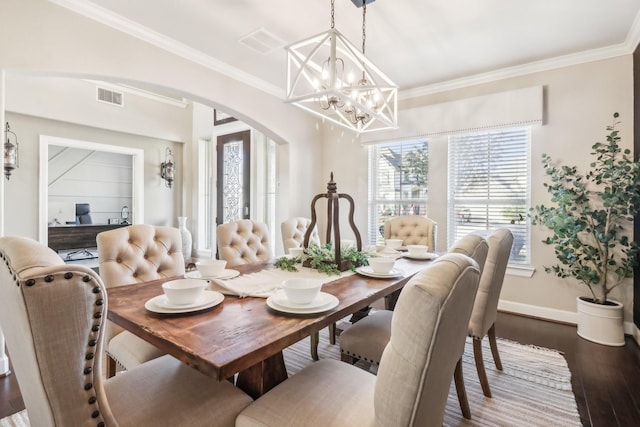 dining area with visible vents, crown molding, baseboards, wood finished floors, and arched walkways