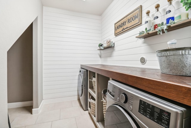 washroom featuring washer and dryer, baseboards, light tile patterned flooring, and laundry area