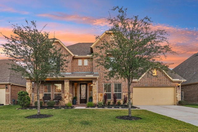 view of front of home featuring brick siding, a lawn, concrete driveway, and a garage