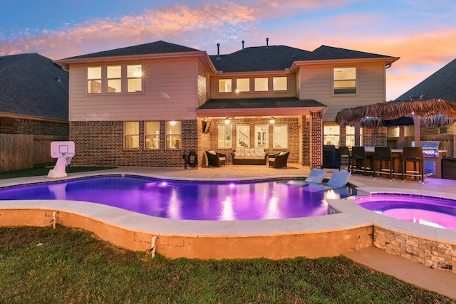 back of house at dusk featuring brick siding, a fenced in pool, an in ground hot tub, and outdoor lounge area