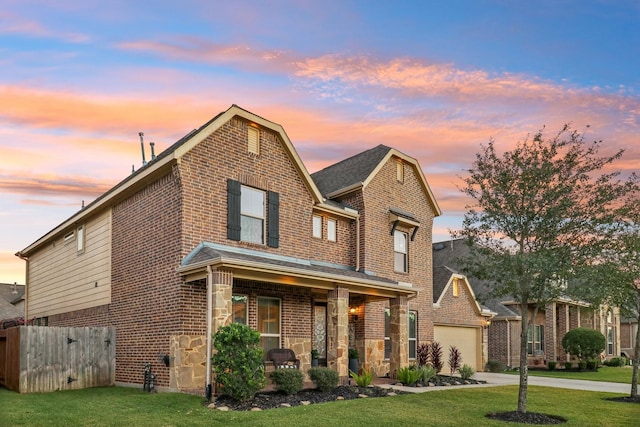 view of front of home featuring stone siding, brick siding, a porch, and concrete driveway