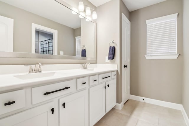 bathroom with tile patterned flooring, double vanity, baseboards, and a sink