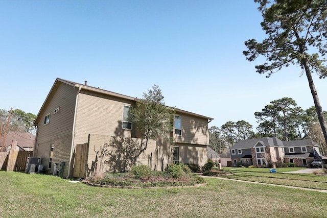 view of side of home featuring cooling unit, brick siding, a yard, and fence