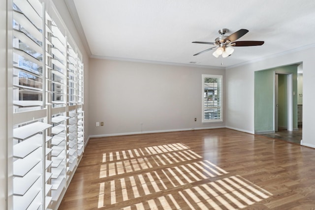 unfurnished room with ornamental molding, baseboards, and wood finished floors