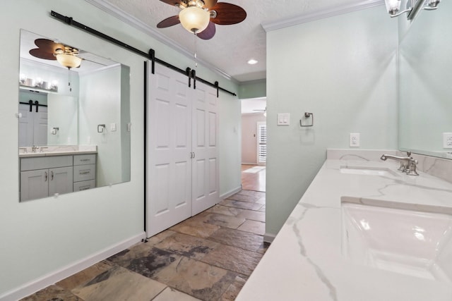 bathroom with stone tile flooring, a ceiling fan, ornamental molding, and a sink