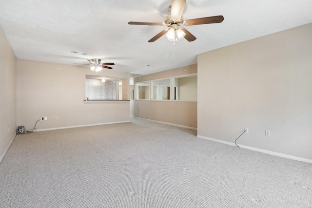 carpeted empty room with a ceiling fan, visible vents, and baseboards