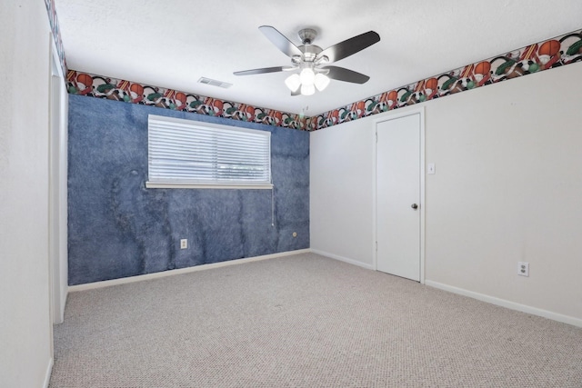 unfurnished room featuring carpet floors, visible vents, baseboards, and a ceiling fan