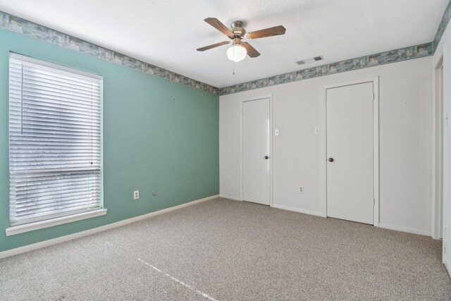 unfurnished bedroom featuring ceiling fan, carpet, visible vents, and baseboards