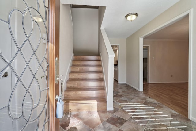 foyer entrance with crown molding, stairway, wood finished floors, and baseboards