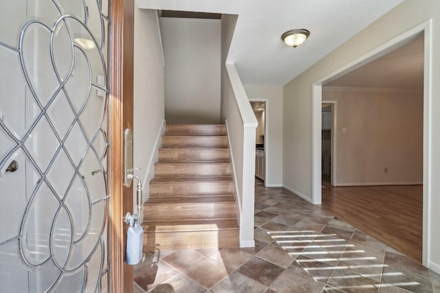 entrance foyer featuring baseboards, stairway, and crown molding