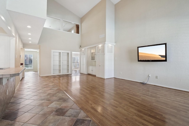unfurnished living room with visible vents, baseboards, high vaulted ceiling, and dark wood finished floors