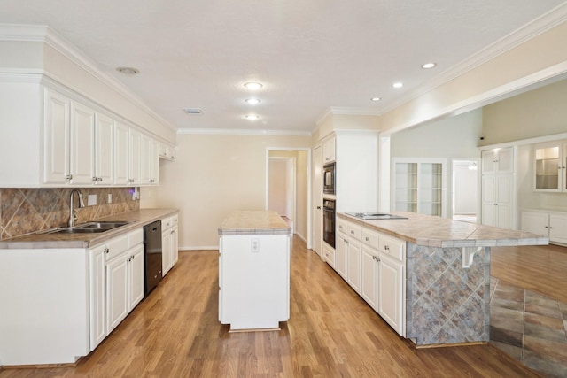 kitchen with a sink, light wood-type flooring, white cabinetry, a kitchen island, and black appliances