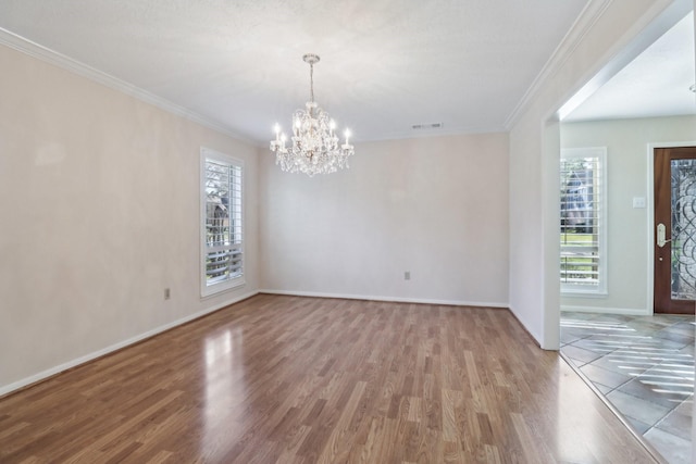 empty room with visible vents, crown molding, baseboards, and wood finished floors