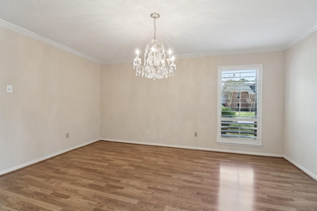 unfurnished room featuring baseboards, wood finished floors, an inviting chandelier, and crown molding