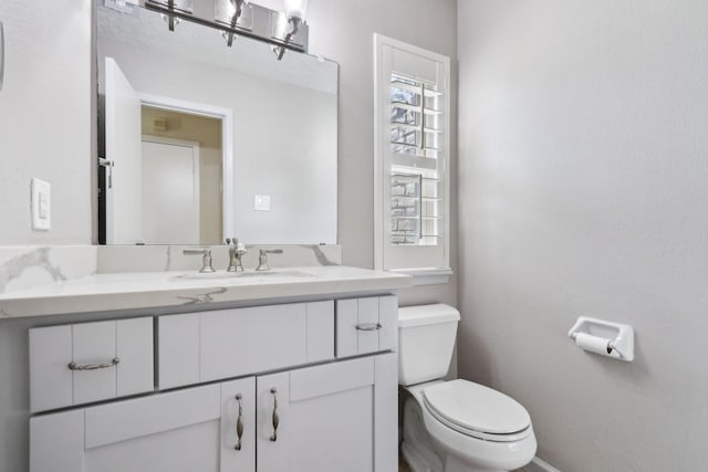 bathroom with baseboards, vanity, and toilet