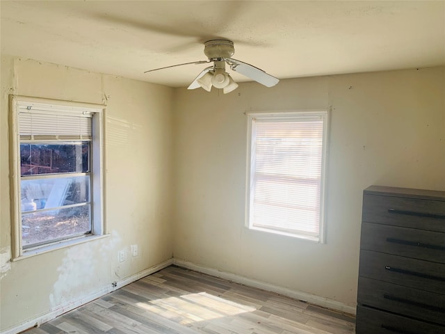 spare room with a healthy amount of sunlight, light wood finished floors, ceiling fan, and baseboards